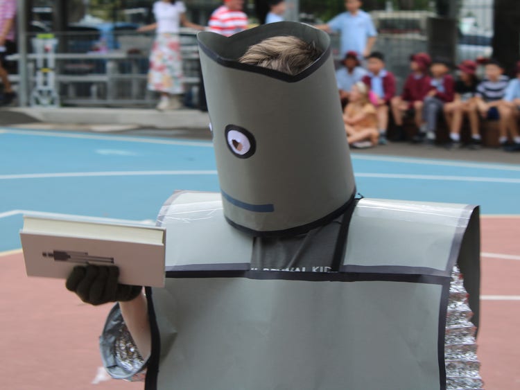 Student in a home made robot costume holding a book