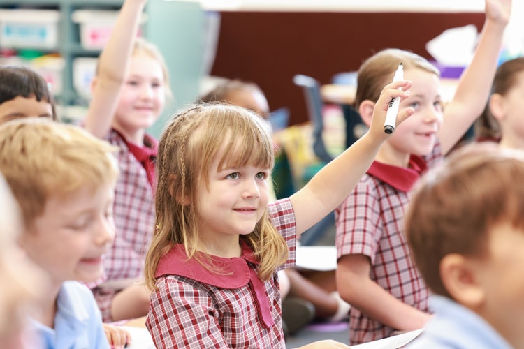 Kindy students with some raising their hands