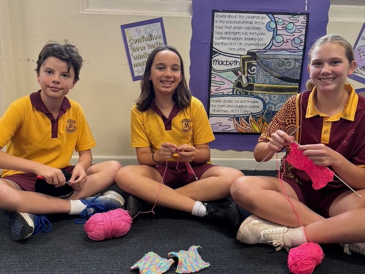 Three students sliming at the camera while knitting